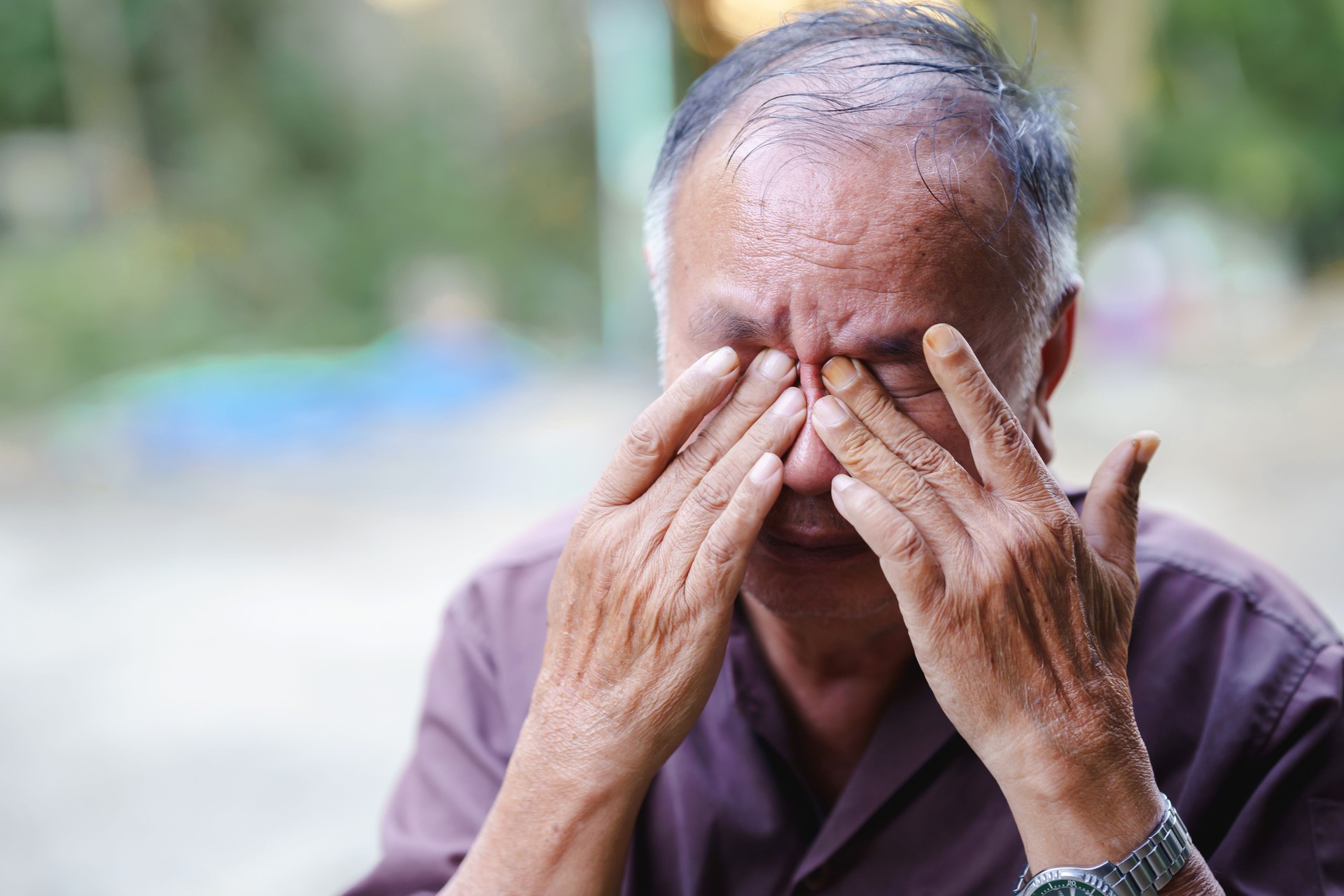elderly man expresses deep emotion while covering his face with his hands